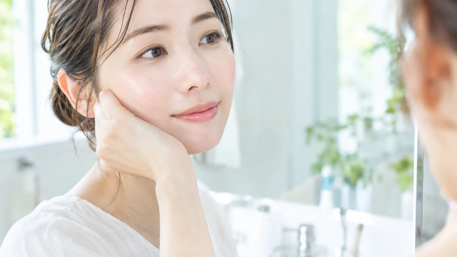 頬に片手を当て、満足そうな表情で自分の肌を見つめているところ