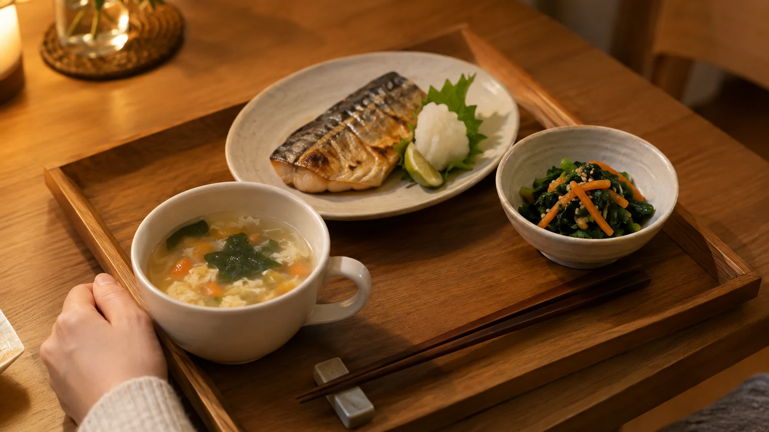 食卓で、スープのカップの横に主菜と副菜が並んでいるところ