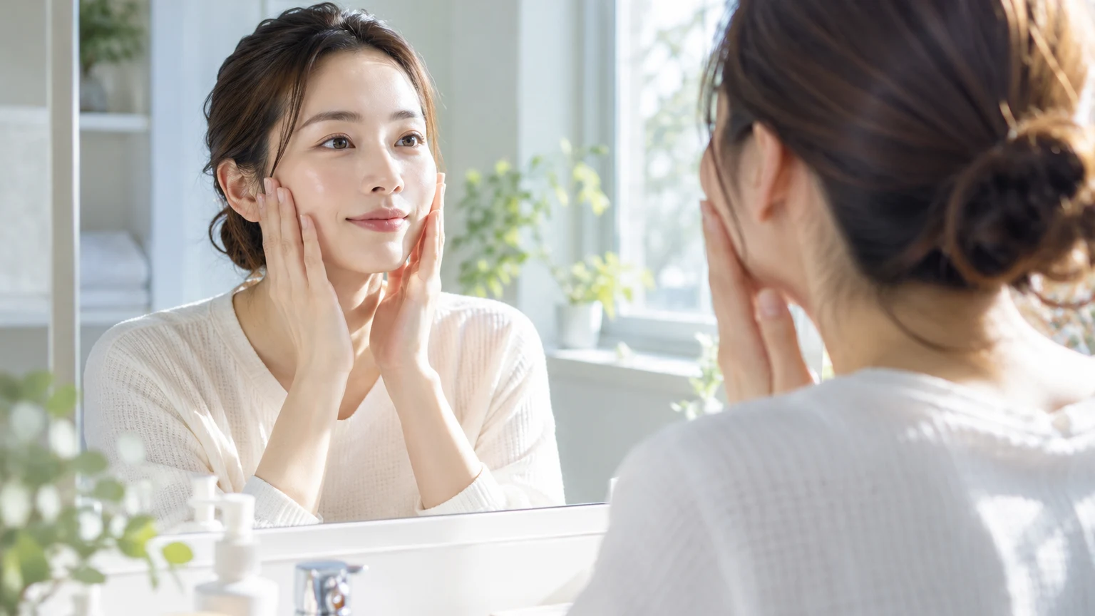 鏡の前で両手を頬に添え、2週間比べた肌の様子を確かめて微笑んでいる様子