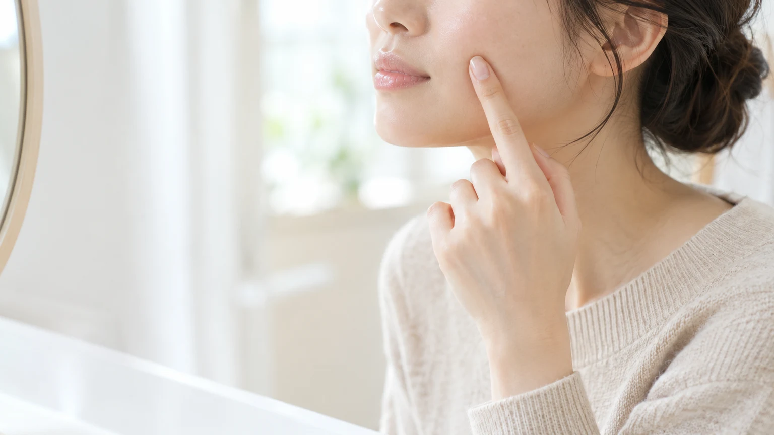 鏡の前で、頬に指を1本当てて当てたい場所を確かめている顔の下半分