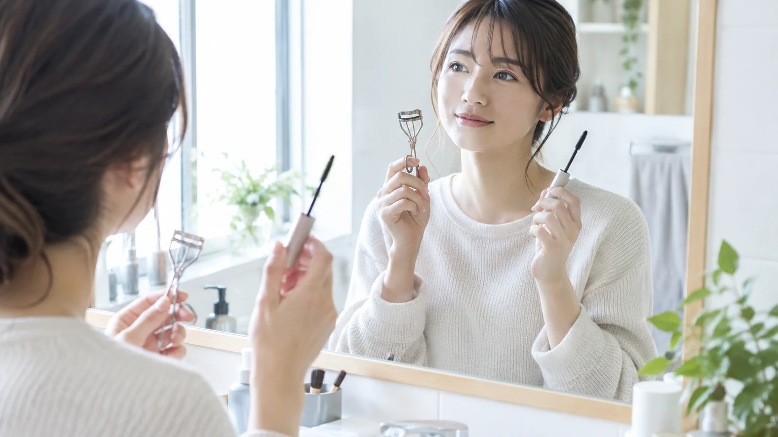 朝の洗面所で、ビューラーとマスカラを手にしているところ