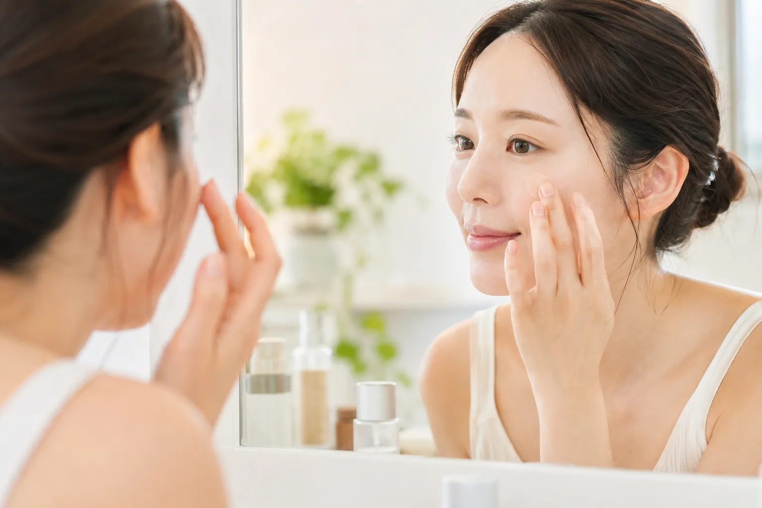 鏡の前で指先を使い、頬のシミにコンシーラーを点置きしてなじませる女性の手元