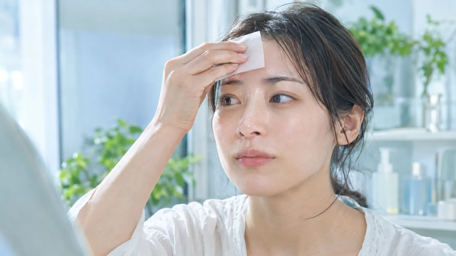 汗ばんだ額をティッシュで拭う女性、皮脂や汗によるかゆみを気にする様子