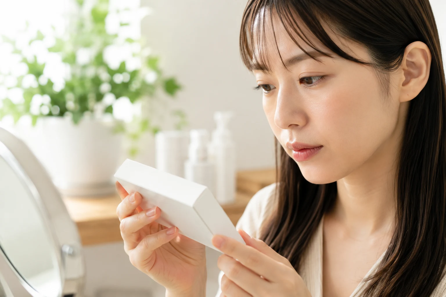 白いパッケージを両手で持ち、真剣な表情で確認する女性の横顔