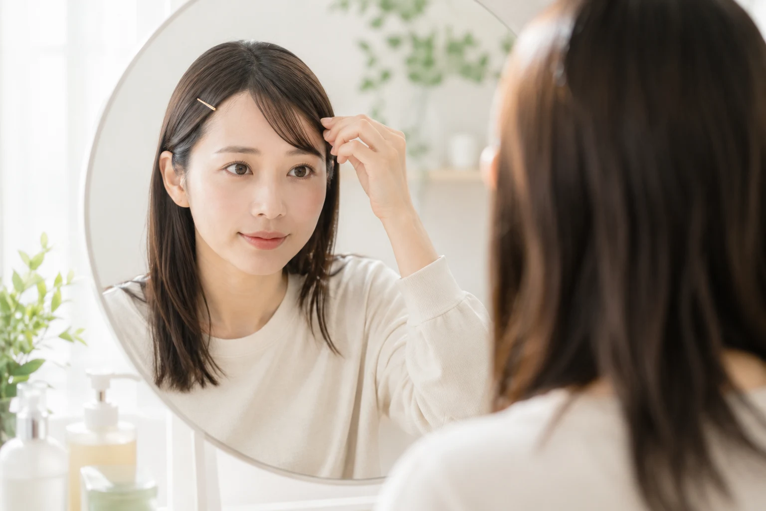 伸ばしかけの前髪をヘアピンでサイドに留めてアレンジする女性