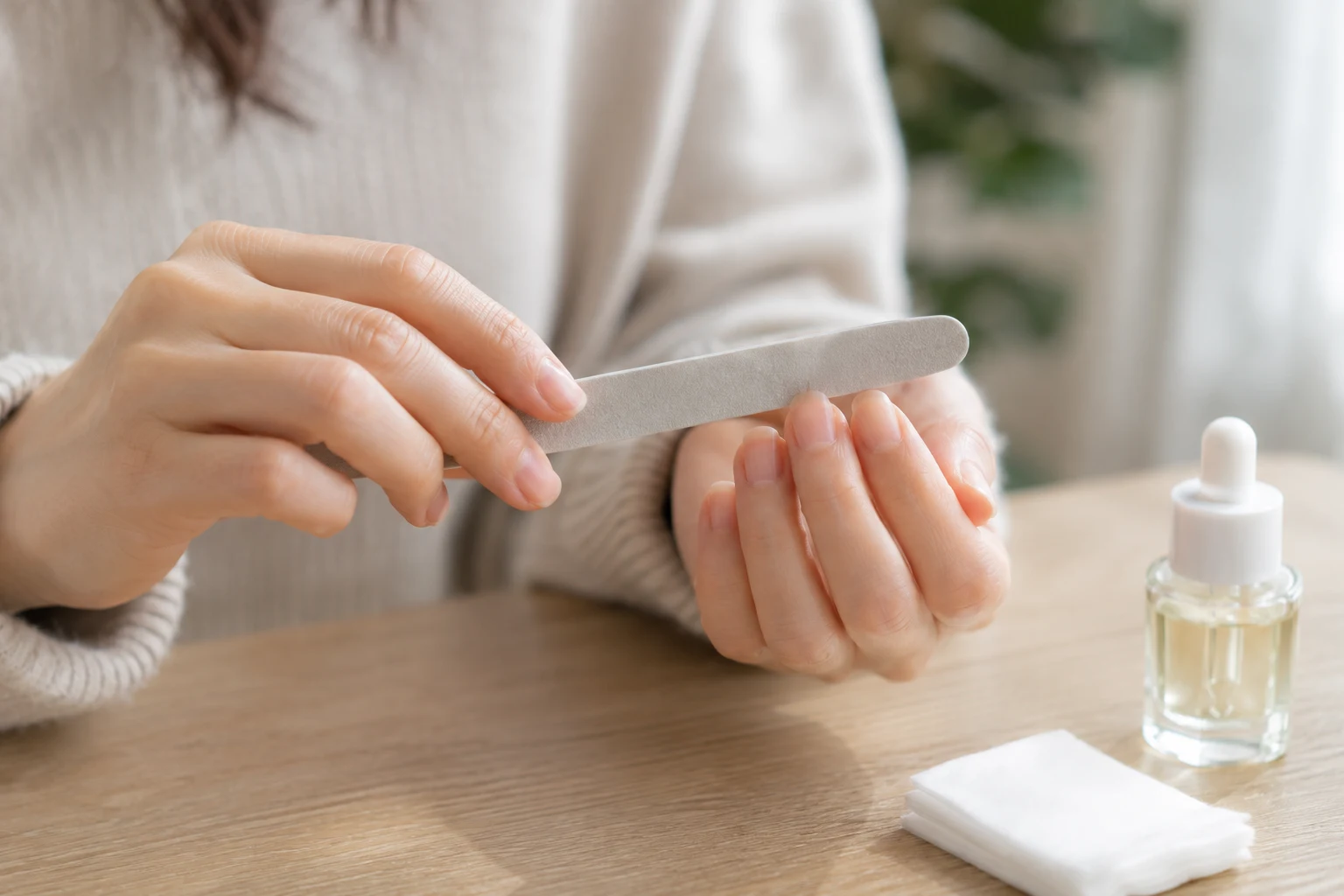 ネイルファイルで爪の先端を一方向に整えている手元