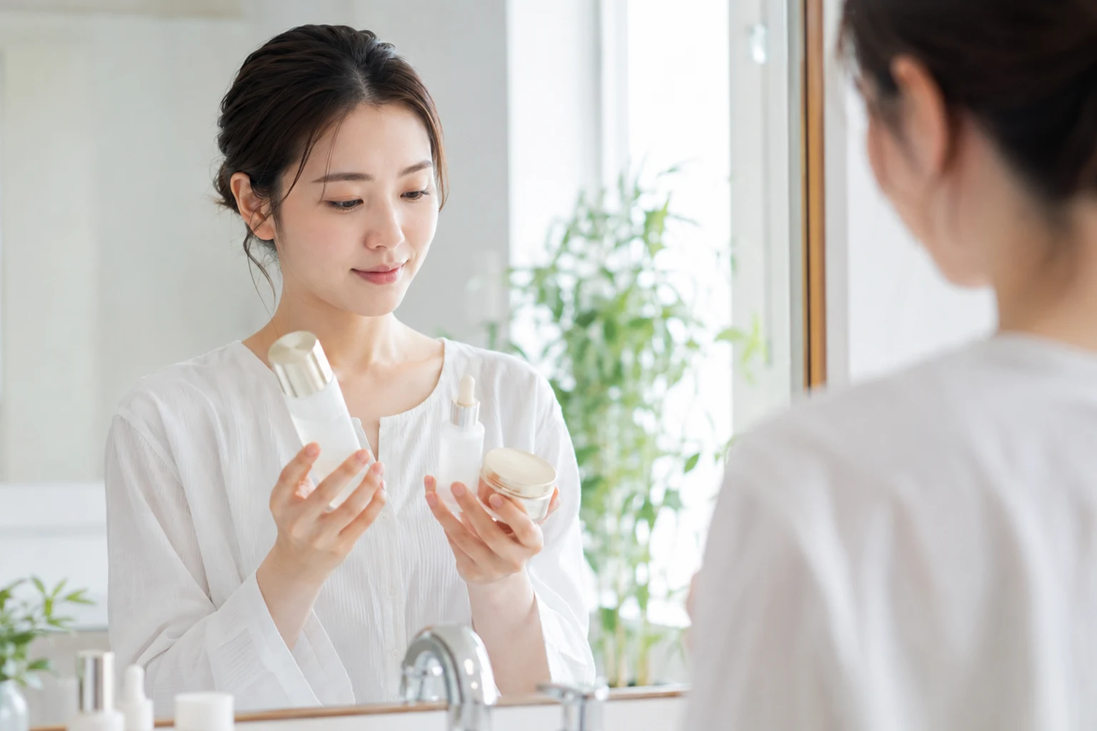 2種類のスキンケア製品を手に取って見比べる女性