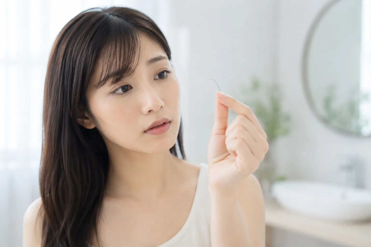 洗面所でコンタクトレンズを指先に乗せて確認している様子